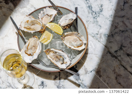 Fresh oysters on ice with champagne in sunlight Fresh oysters on ice with champagne in sunlight 137061422