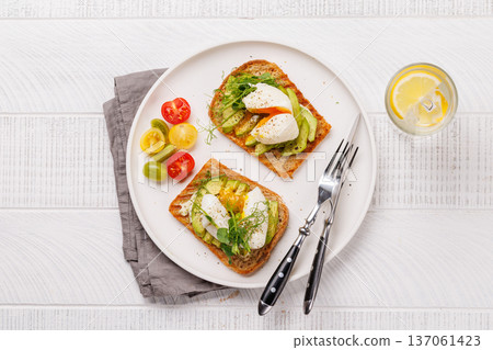 Delicious avocado toasts topped with perfectly cooked poached eggs Delicious avocado toasts topped with perfectly cooked poached eggs 137061423