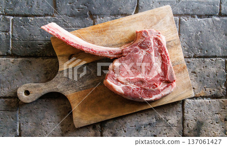 Raw tomahawk steak on cutting board Raw tomahawk steak on cutting board 137061427