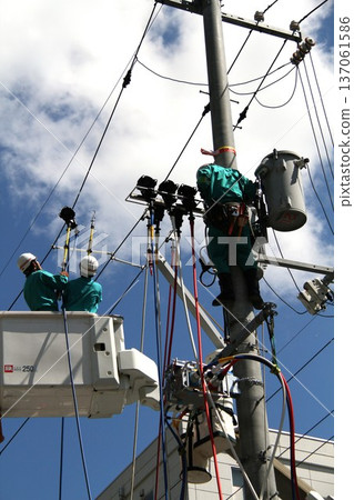 An electric power company worker inspecting utility pole equipment under a blue sky An electric power company worker inspecting utility pole equipment under a blue sky 137061586