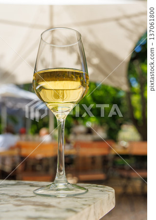 Glass of white wine on sunny terrace Glass of white wine on sunny terrace 137061800