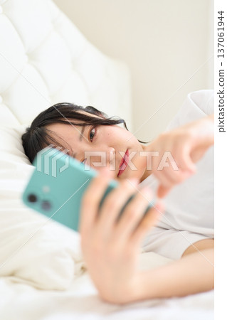 A woman looking at a smartphone with an uneasy look A woman looking at a smartphone with an uneasy look 137061944