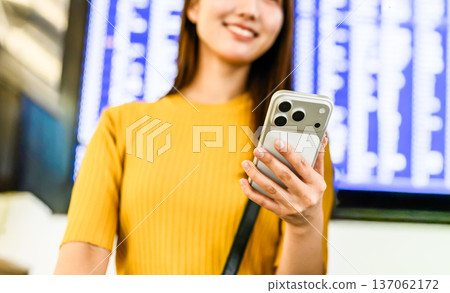 一名女子在機場查看她的智慧型手機。照片由關西國際機場(KIX)提供。 一名女子在機場查看她的智慧型手機。照片由關西國際機場(KIX)提供。 137062172