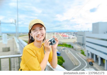 A woman holding a camera at the airport. Photo courtesy of Kansai International Airport (KIX). A woman holding a camera at the airport. Photo courtesy of Kansai International Airport (KIX). 137062173