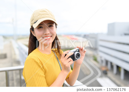 A woman holding a camera at the airport. Photo courtesy of Kansai International Airport (KIX). A woman holding a camera at the airport. Photo courtesy of Kansai International Airport (KIX). 137062176