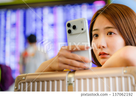 一名女子在機場查看她的智慧型手機。照片由關西國際機場(KIX)提供。 一名女子在機場查看她的智慧型手機。照片由關西國際機場(KIX)提供。 137062192