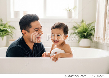 Happy hispanic father washing his toddler son in a white bathtub at home 137062730