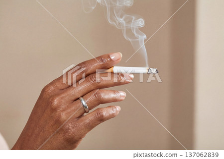 African american woman hand holding lit cigarette with rising smoke 137062839