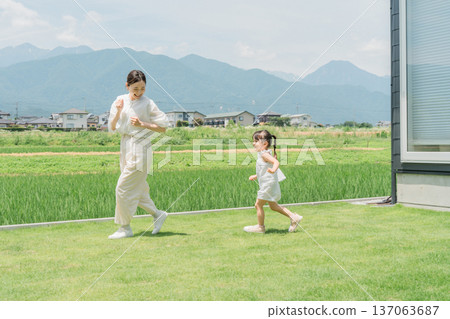 父母和孩子,媽媽和女兒在自家草坪花園玩捉迷藏 父母和孩子,媽媽和女兒在自家草坪花園玩捉迷藏 137063687