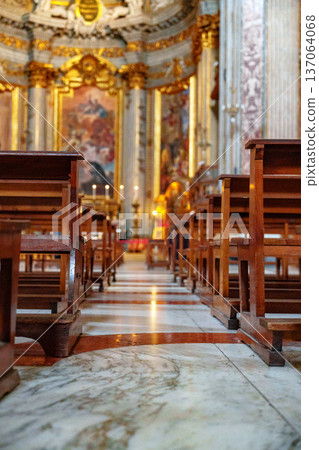 Wooden chairs line the floor in a church with ornate decorations and light coming through Wooden chairs line the floor in a church with ornate decorations and light coming through 137064068