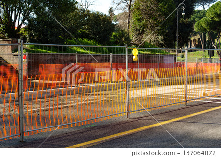 Construction work is taking place at a road site during the daytime near a park in a city Construction work is taking place at a road site during the daytime near a park in a city 137064072