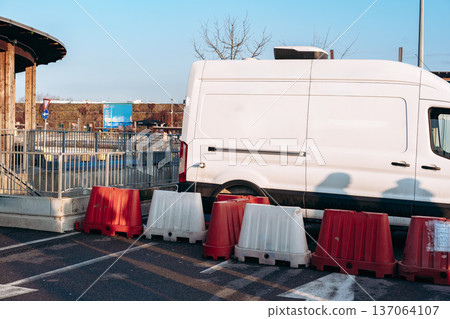 White van parked near barriers in a lot during daylight hours 137064107