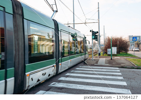 Tram travels through intersection with green signal in urban area during daytime 137064127