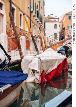 Boat covered with tarp rests by the canal in Venice during a quiet afternoon Boat covered with tarp rests by the canal in Venice during a quiet afternoon 137064152