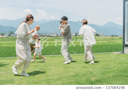 Family playing tag and chasing in the lawn of their home Family playing tag and chasing in the lawn of their home 137064296