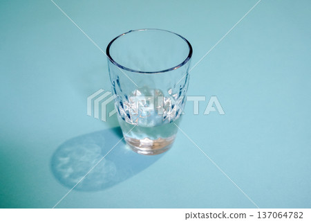 Minimalist Glass of Water on a Pastel Blue Background 137064782