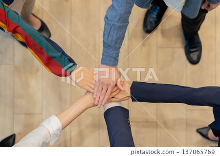 Business hands stacked in a circle, overhead view Business hands stacked in a circle, overhead view 137065769