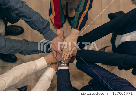 Business hands stacked in a circle, overhead view Business hands stacked in a circle, overhead view 137065771