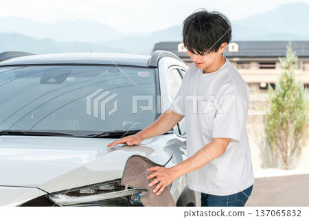 Young Asian man washing his car in his garage Young Asian man washing his car in his garage 137065832