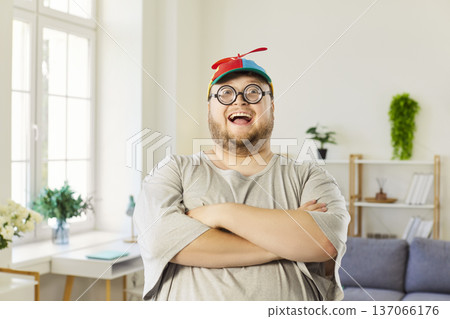 Cheerful plus-size man in propeller beanie and nerd glasses with arms crossed 137066176