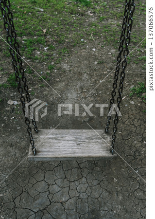 Lonely Wooden Swing Over Cracked Earth in Dark Melancholic Atmosphere 137066576