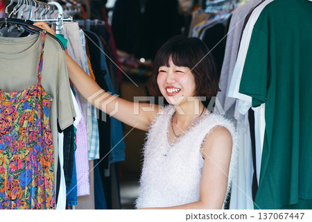 Young woman searching for clothes in a second-hand clothing store Young woman searching for clothes in a second-hand clothing store 137067447
