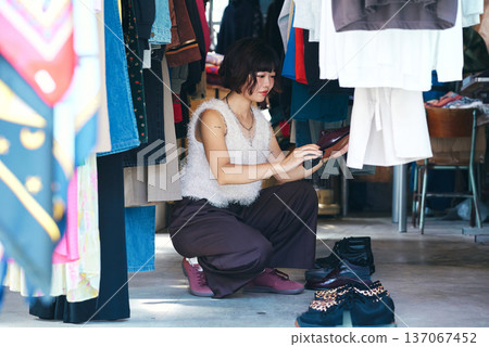 Young woman searching for clothes in a second-hand clothing store Young woman searching for clothes in a second-hand clothing store 137067452