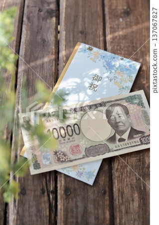 A light blue, floral gift envelope and a new 10,000 yen bill. A gift for graduation or graduation celebration. A light blue, floral gift envelope and a new 10,000 yen bill. A gift for graduation or graduation celebration. 137067827