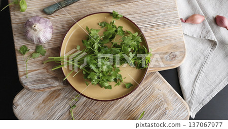 Fresh green parsley on ceramic plate. High-quality farm produce on wooden cutting board. Top view. Flat lay photography. Traditional Italian cuisine. 137067977