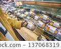一位女士在超市裡挑選了一份貼有折扣標籤的盒裝午餐或預製食品。 137068319