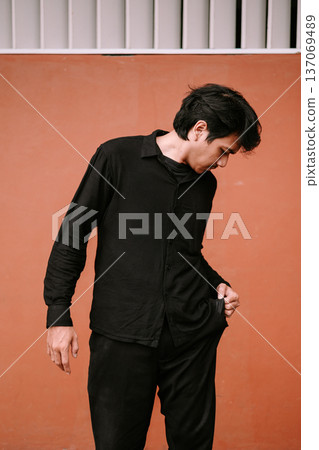 Thoughtful Young Man in Black Attire Looking Down Thoughtful Young Man in Black Attire Looking Down 137069489