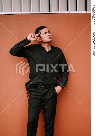 Thoughtful Man Pondering Ideas Against a Vibrant Wall 137069665