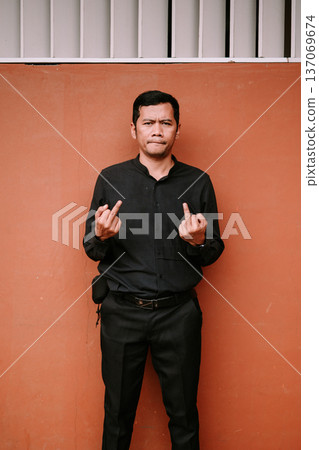 Man Showing Disrespectful Middle Finger Gesture Against Wall Man Showing Disrespectful Middle Finger Gesture Against Wall 137069674