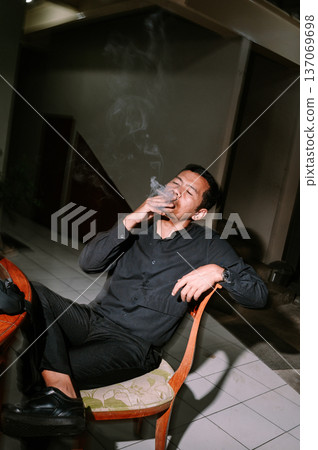 Man enjoying a contemplative smoke break indoors Man enjoying a contemplative smoke break indoors 137069698