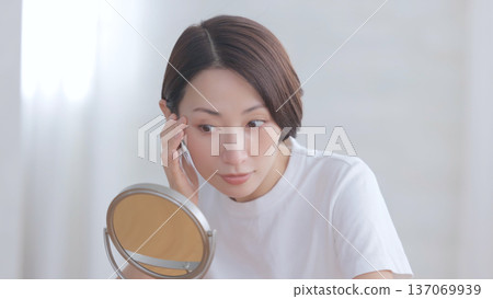 A woman looking at a mirror and smiling A woman looking at a mirror and smiling 137069939
