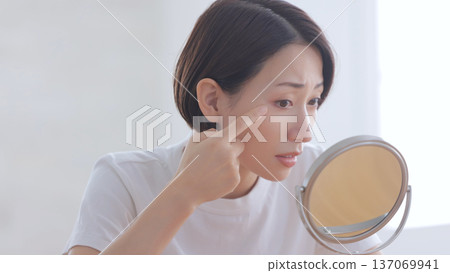 A woman looking at a mirror and smiling 137069941