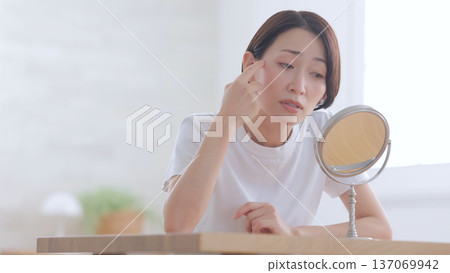 A woman looking at a mirror and smiling A woman looking at a mirror and smiling 137069942