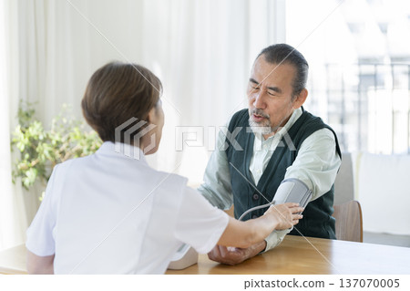 Senior man having his blood pressure measured by medical staff Senior man having his blood pressure measured by medical staff 137070005