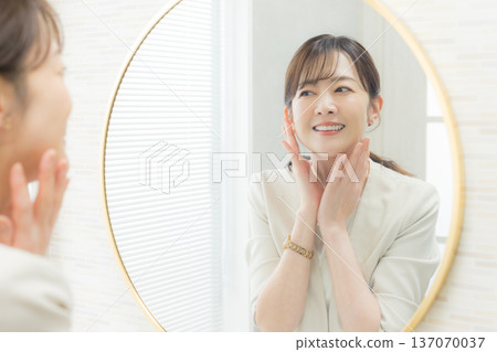 Woman applying makeup in the mirror 137070037