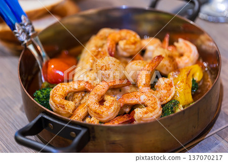 Spanish-style seafood stew cooked in an elegant copper pot Spanish-style seafood stew cooked in an elegant copper pot 137070217