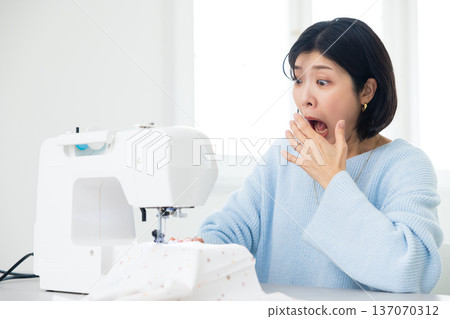 A woman sewing with a sewing machine A woman sewing with a sewing machine 137070312