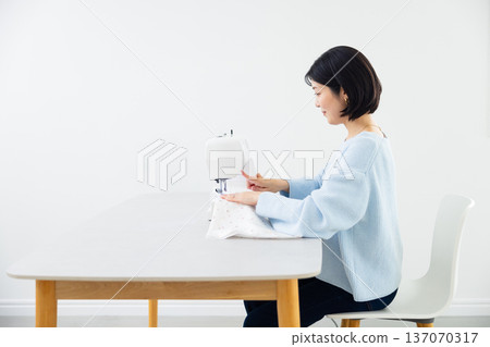 A woman sewing with a sewing machine A woman sewing with a sewing machine 137070317