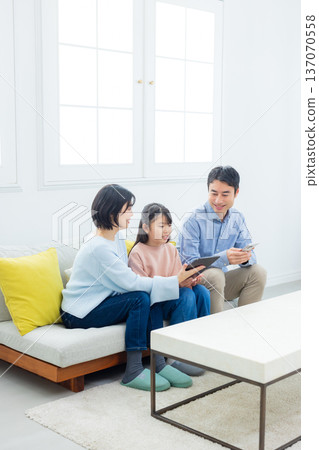 family looking at tablet in living room family looking at tablet in living room 137070558