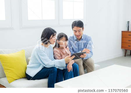 family looking at tablet in living room family looking at tablet in living room 137070560