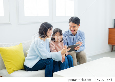 family looking at tablet in living room family looking at tablet in living room 137070561