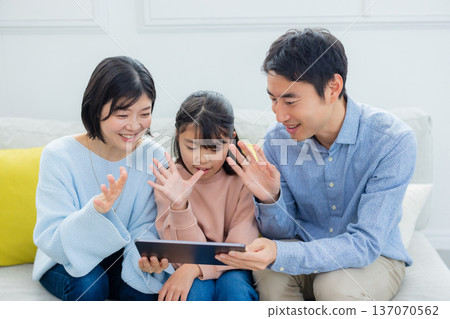 family looking at tablet in living room family looking at tablet in living room 137070562