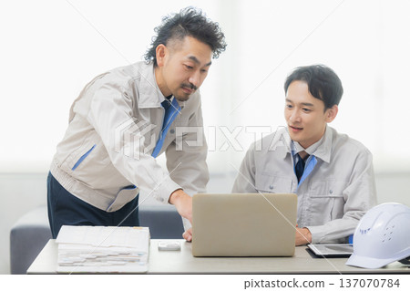 Engineers having a meeting while looking at documents at the office Engineers having a meeting while looking at documents at the office 137070784