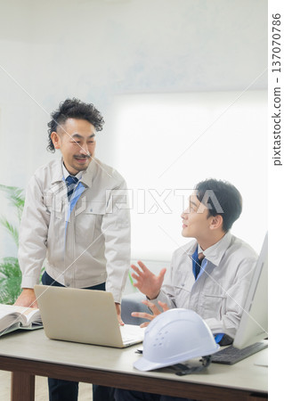 工程師們在辦公室一邊開會一邊查看文件。 工程師們在辦公室一邊開會一邊查看文件。 137070786
