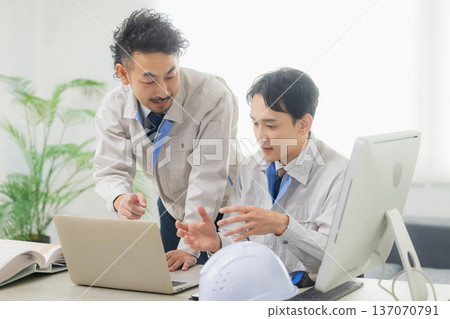 Engineers having a meeting while looking at documents at the office Engineers having a meeting while looking at documents at the office 137070791