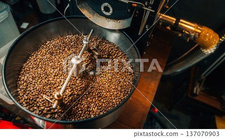 reshly roasted coffee beans mixing in a commercial coffee roaster machine. 137070903